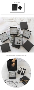 Matte black jewelry gift box and matching paper bag on elegant white linen texture