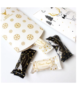 Close-up of Christmas pillow boxes with gold snowflakes and peanut nougat candy bags