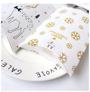 Close-up of white Christmas pillow gift boxes with gold reindeer and snowflake patterns