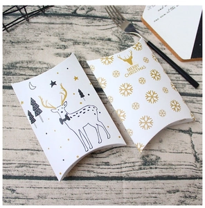 Close-up of Merry Christmas pillow gift boxes with gold snowflake prints on a wooden table