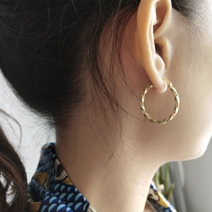 Polished golden twisted hoop earrings for women in 925 sterling silver worn by a model