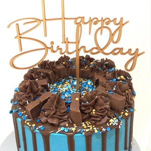 Macro shot of rose gold acrylic Happy Birthday topper on a decorated cake