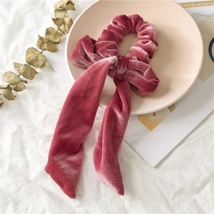 Close-up of velvet hair scrunchie with large bow detail in dusty rose finish