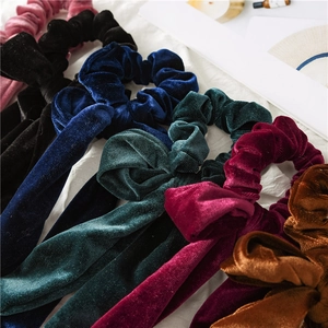 Detailed view of velvet scrunchies with oversized bows in various vintage colors