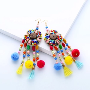 Detalle de pendientes bohemios con cuentas de colores, discos de madera y borlas de seda