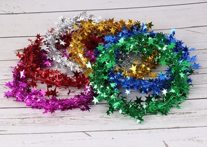 Close-up of colorful star wire tinsel garlands in blue gold and red on white wood