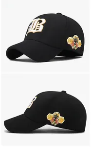 Detail of 3D embroidered white letter B and bee motif on black cotton baseball cap