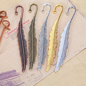 Detailed view of vintage metal feather bookmarks in five metallic finishes on kraft paper