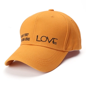 Detail of embroidered LOVE text on washed cotton orange baseball cap with curved brim