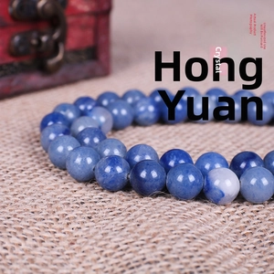 Macro shot of natural blue aventurine round beads on beige textured woven surface
