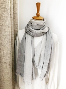 Detailed close-up of grey gradient cotton linen scarf with soft fringe on a wooden stand