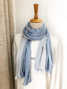 Detailed macro view of the blue and white gradient striped scarf with frayed edges