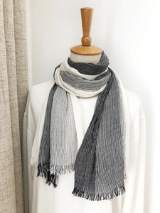 Close-up of black and white striped cotton-linen scarf texture with fringe on a wooden mannequin