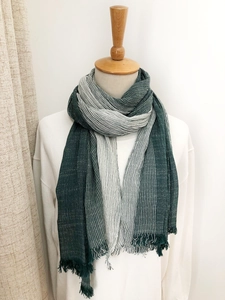 Detail of dark green and white striped cotton-linen scarf with fringed edges on mannequin