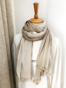 Detail of beige and brown striped scarf with fringe edges on a wooden mannequin