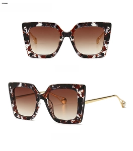 Detail of tortoise shell oversized cat eye sunglasses with gradient tea lenses and pearl tips