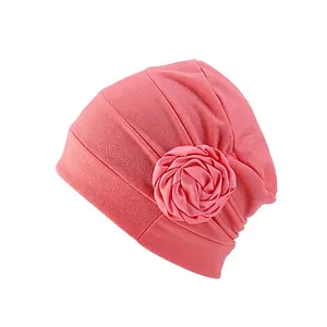 Détail d'un turban plissé rose avec une grande fleur en tissu multicouche décorative