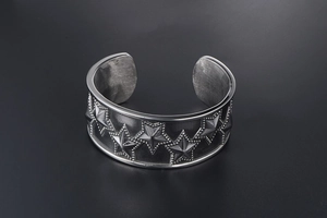 Close-up of vintage punk silver steel cuff bracelet featuring embossed stars and beaded edges