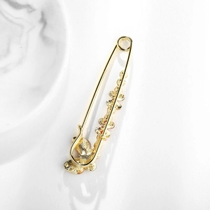 Golden flower brooch pin with sparkling rhinestone details and alloy metal leaf accents