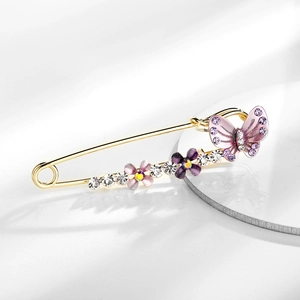 Detailed shot of golden brooch pin with purple and pink enamel butterflies and flowers