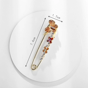 Macro detail of alloy flower safety pin brooch with sparkling rhinestones and golden butterfly