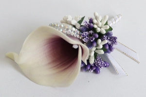 Close-up of handmade purple calla lily boutonniere with crystal accents and gold-trimmed ribbon