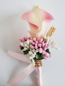 Detail of pink calla lily boutonniere with green leaves, pearls, and ribbon on white background