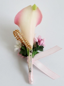 Close-up of white Calla Lily boutonniere with rhinestone gold band and pink ribbon bow