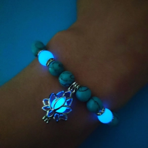 Detail of turquoise bead yoga bracelet with glowing blue lotus charm in the dark