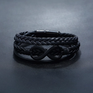 Close-up of black braided leather bracelet featuring a matte black infinity symbol buckle