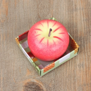 Primer plano de una vela realista de manzana roja en su caja de regalo sobre madera