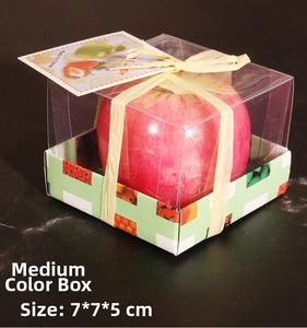 Detalle de vela de manzana roja mediana en caja de regalo transparente con base de cuadros