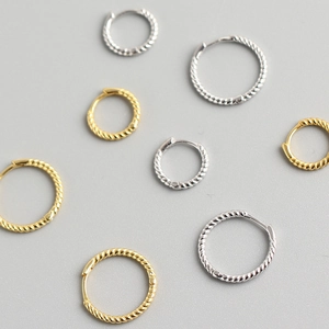 Flat lay of gold and silver twisted hoop earrings with textured spiral design detail