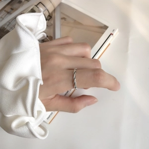 Detail of twisted rope design silver ring worn by a model in a minimalist lifestyle setting