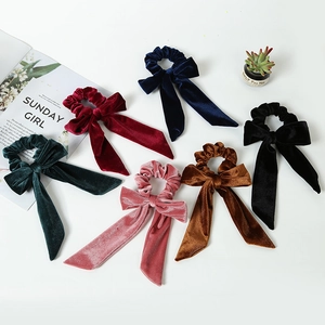 Set of six colorful velvet bow scrunchies with long ribbons on a minimalist background