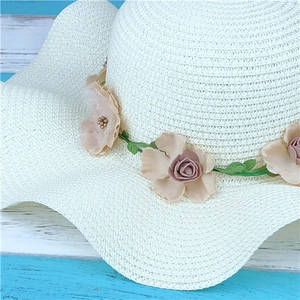 White woven straw sun hat with floral garland and large brim for summer beach protection
