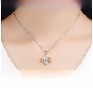 Detail of bee pendant in sterling silver with gold plating worn on woman's neckline