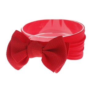 Detail of red elastic nylon baby headband with a large soft knitted bow for infants