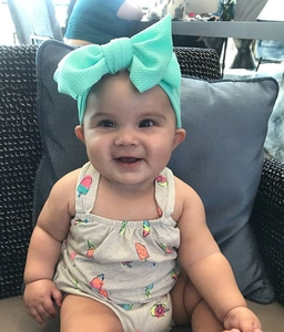 Detailed view of an infant wearing a stylish turquoise waffle knit bow headband