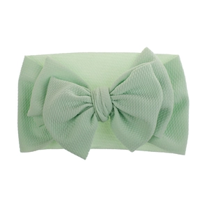 Detail of mint green baby headband with waffle texture and oversized bow ornament