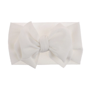 Close-up view of a soft white infant headband featuring a large textured fabric bow detail
