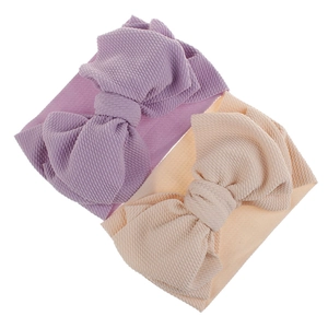 Close-up of baby bow headbands in purple and beige with soft ribbed waffle fabric