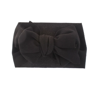 Close-up of black baby headband featuring a textured fabric bow on a white background