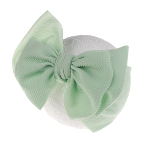 Detail of mint green baby headband with waffle texture and large layered bow design