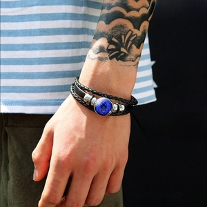 Close-up of multilayer woven leather bracelet featuring a blue lion charm on a male wrist