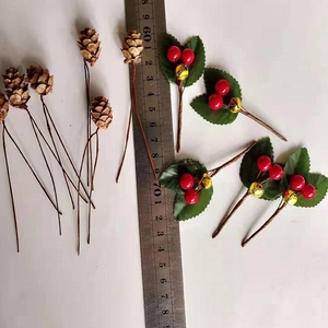 Artificial pine cones and red berries with green leaves and bell on white background