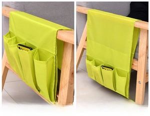 Detail of green armchair caddy hanging on sofa for storing smartphones and remotes