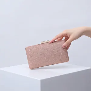 Pink glitter evening clutch bag with golden metal clasp on minimalist white pedestal