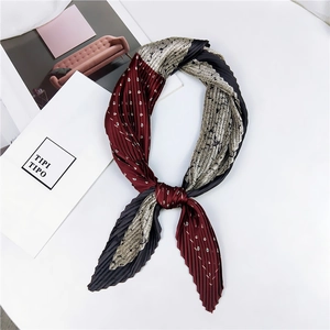 Détail d'un foulard en soie plissé avec motif paisley bordeaux et design patchwork