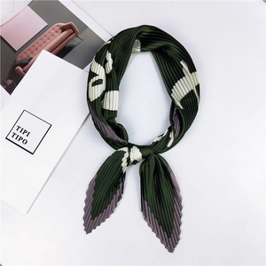 Détail d'un foulard en soie plissé vert avec motifs floraux noué avec style